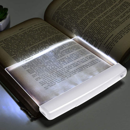Lámpara LED iluminando libro con luz blanca intensa en la oscuridad