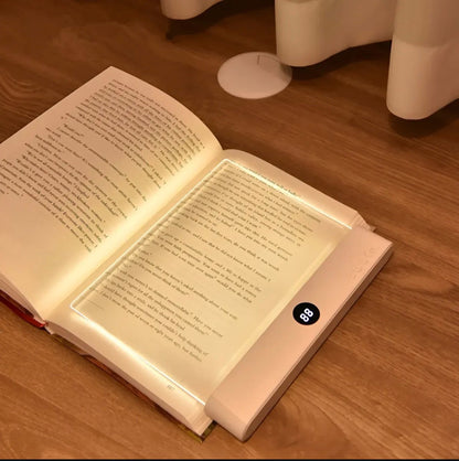 Lámpara LED sobre libro abierto con luz cálida en mesita de noche